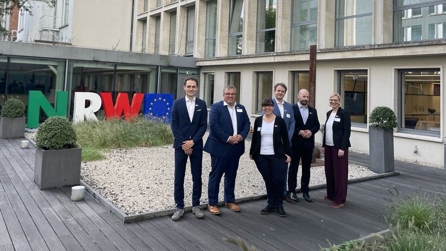 Group photo in front of NRW flag and EU flag outside a modern building in Brussels
